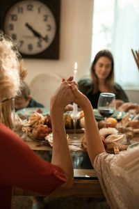 Image of food, celebration and prayer for Thanksgiving and Friendsgiving 2024 Blog post at Bloggey.com - Images free courtesy of Pexels.com at https://www.pexels.com/photo/woman-in-red-long-sleeve-shirt-holding-lighted-cigarette-stick-5847676/